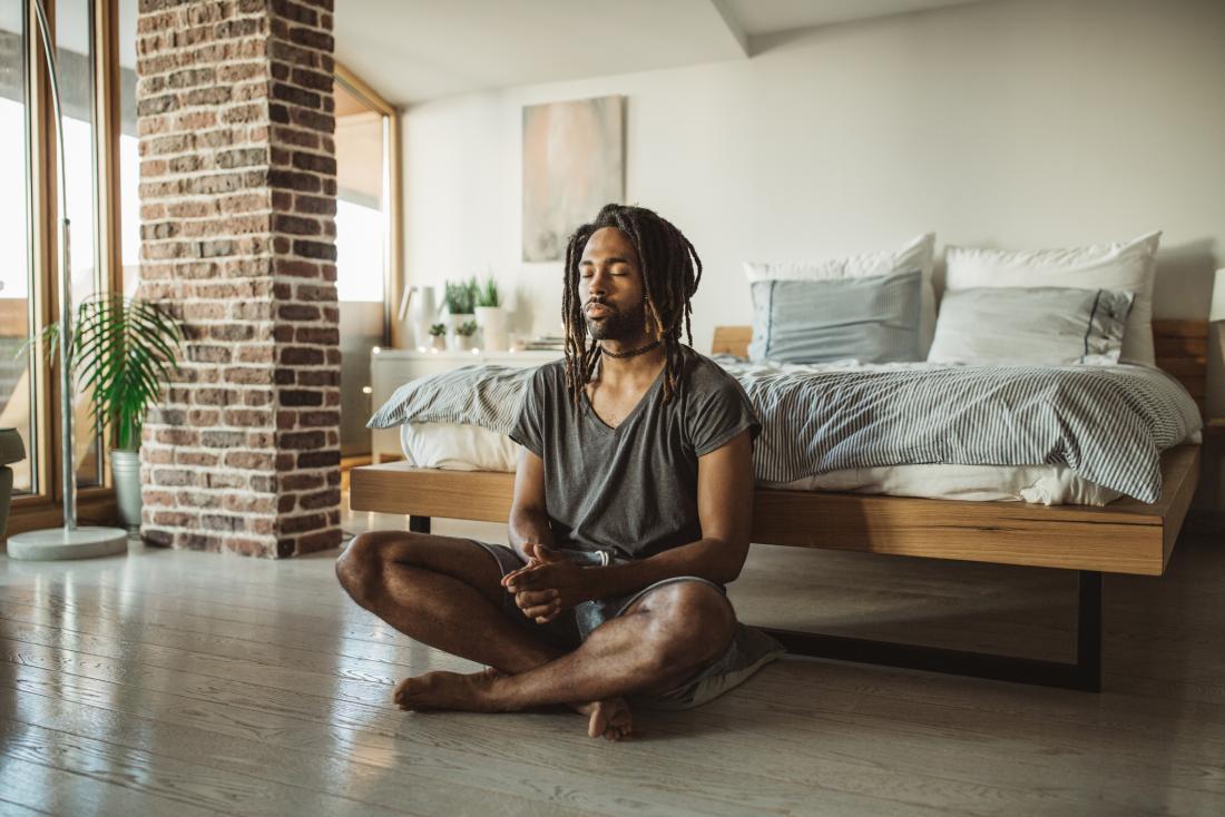 person meditating on bedroom floor